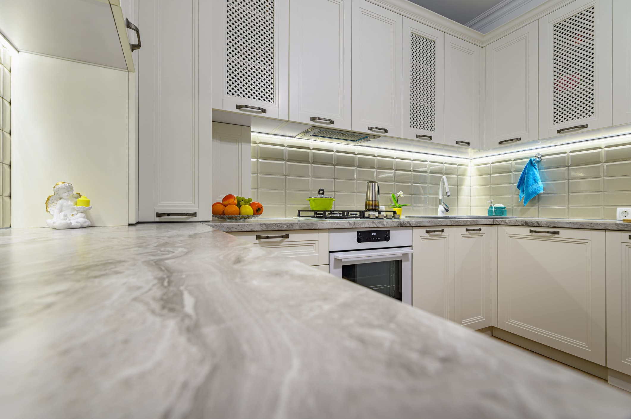 White Kitchen Cabinetry Design White painted kitchen cabinetry with cream subway tile backsplash, marble countertops, and stainless steel appliances.