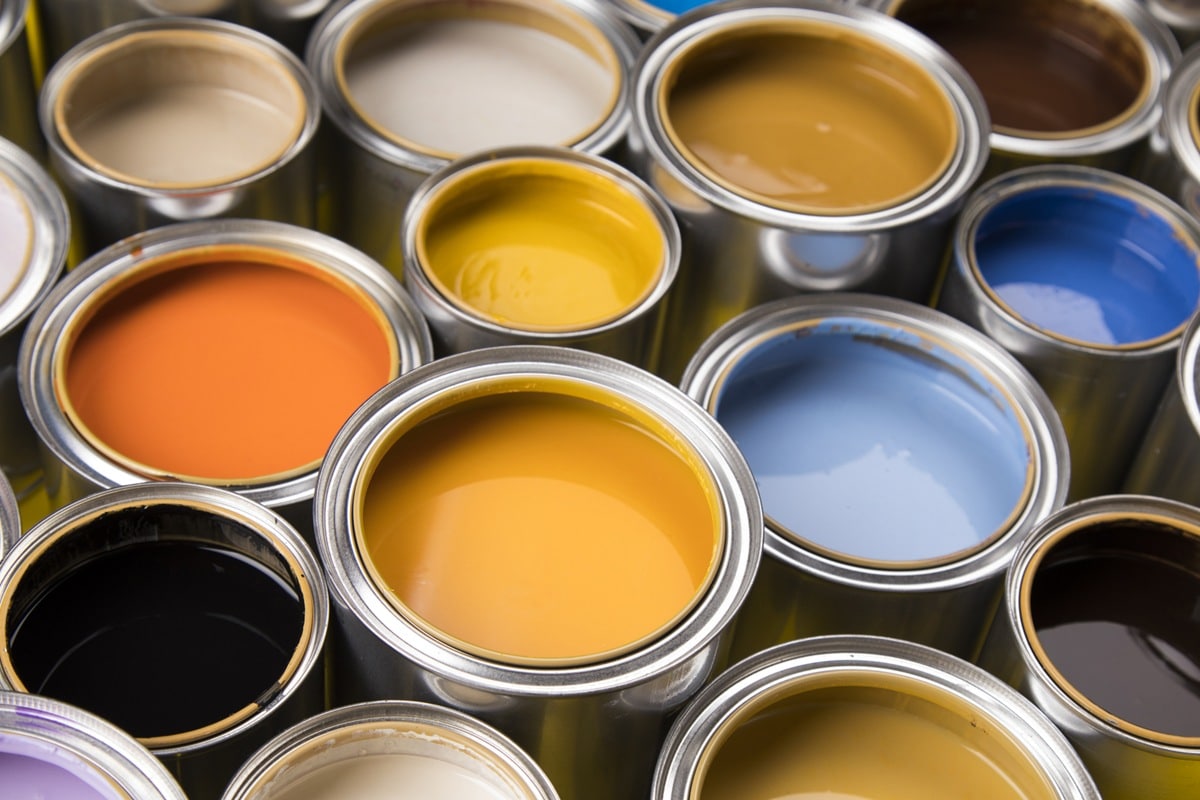 Interior Exterior Paint Color Swatches Multiple paint color swatches in open cans including orange, yellow, blue, black, and neutral beige tones.
